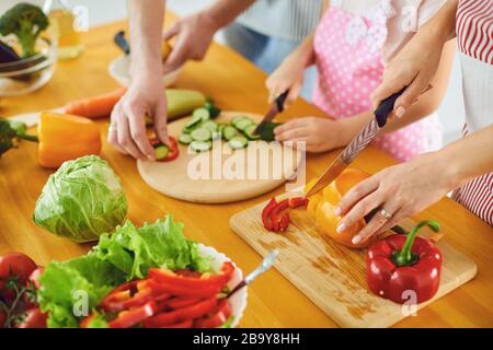 Sans visage. Les mains familiales préparent une salade de légumes frais sur la table dans la cuisine. Les mains de la mère couper des légumes avec un couteau. Saine alimentation Banque D'Images