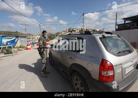 Tulkarem. 25 mars 2020. Un policier palestinien travaille à un point de contrôle à l'entrée de la ville de Tulkarem, en Cisjordanie, le 25 mars 2020. La Palestine a déclaré mercredi que deux nouveaux cas de COVID-19 étaient positifs, portant à 62 le nombre total d'infectés dans ses territoires. Crédit: Nidal Eshtayeh/Xinhua/Alay Live News Banque D'Images