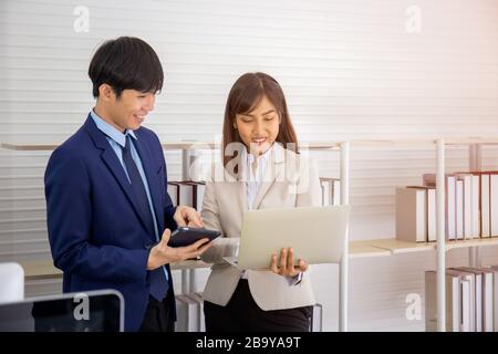 Deux jeunes hommes d'affaires asiatiques se réunissent au bureau à la main de la tablette. Banque D'Images
