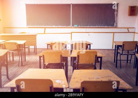 Retour au concept scolaire. Vue floue de la salle de classe ensoleillée avec chaises, tables et tableau noir. Banque D'Images