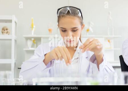 Une belle scientifique féminine travaille dans un laboratoire scientifique avec divers équipements dans le laboratoire. Banque D'Images