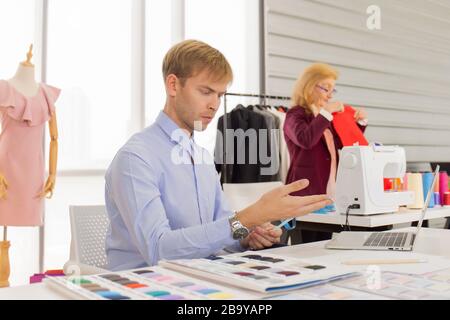 Concepteurs professionnels de travail d'équipe, jeunes hommes et femmes âgées dans le bureau avec une variété de tons de tissu et d'équipement pour divers modèles. Banque D'Images