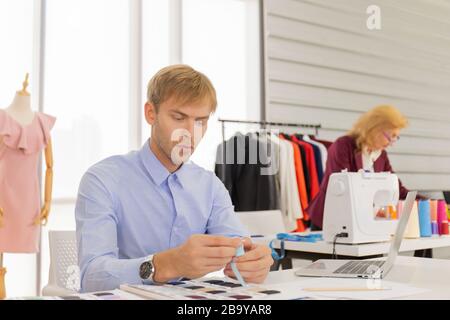 Concepteurs professionnels de travail d'équipe, jeunes hommes et femmes âgées dans le bureau avec une variété de tons de tissu et d'équipement pour divers modèles. Banque D'Images