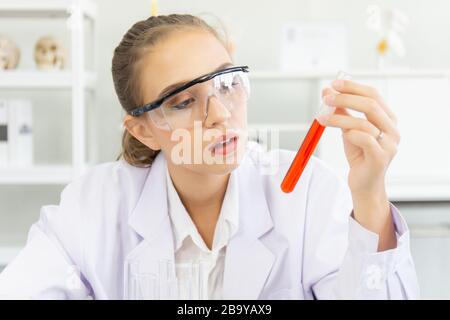 Une belle scientifique féminine travaille dans un laboratoire scientifique avec divers équipements dans le laboratoire. Banque D'Images