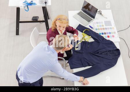 Topview les concepteurs professionnels de travail d'équipe, les jeunes hommes et les femmes âgées dans le bureau avec une variété de tons de tissu et d'équipement pour divers modèles. Banque D'Images