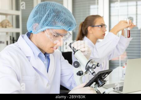 Concept 2: Scientifiques, Chimie, technologie, Biologie - UNE nouvelle génération de scientifiques secouant un verre contenant des réactifs et effectuant des tests ou r Banque D'Images