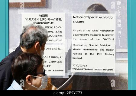 25 mars 2020, Tokyo, Japon: Les gens marchent devant un avis (en japonais et en anglais) du Musée d'art métropolitain de Tokyo qui dit l'exposition spéciale: Vilhelm Hammersoi et la peinture danoise du 19ème siècle est terminée pour empêcher la propagation de la COVID-19. Le gouverneur de Tokyo Yuriko Koike a demandé mercredi aux résidents de s'abstenir de toutes les sorties non essentielles de ce week-end, alors que 41 nouveaux cas d'infections de coronavirus ont été signalés à Tokyo mercredi seulement. Au cours d'une conférence de presse, Koike a averti de verrouiller la ville si les cas d'infection par le coronavirus continuent à augmenter. (Image crédit : © Rodr Banque D'Images