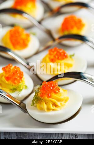 Oeufs farcis avec du caviar rouge dans une cuillère Banque D'Images