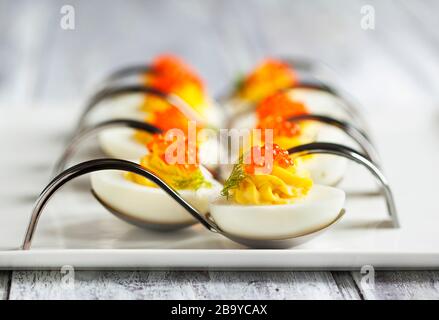 Oeufs farcis avec du caviar rouge dans une cuillère Banque D'Images