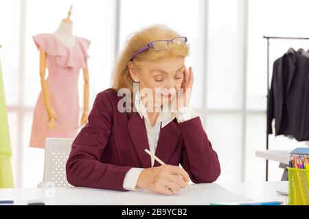 Les femmes designers professionnelles dessinant des croquis sur papier avec des crayons dans une salle de couture. Banque D'Images