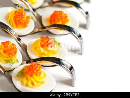 Oeufs farcis avec du caviar rouge dans une cuillère Banque D'Images