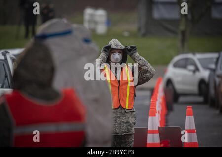 Holmdel, États-Unis. 25 mars 2020. Un Airman de la 108ème Escadre de la Garde aérienne du New Jersey ajuste son capot tout en contrôlant le trafic sur un site d'essai communautaire COVID-19 au Centre des arts de la Banque PNC à Holmdel, N.J., le 23 mars 2020. Le site de test, établi en partenariat avec l'Agence fédérale de gestion des urgences, est doté du Département de la santé du New Jersey, de la police d'État du New Jersey et de la Garde nationale du New Jersey. Photo du Sgt principal. Matt Hecht/États-Unis Air National Guard/UPI crédit: UPI/Alay Live News Banque D'Images