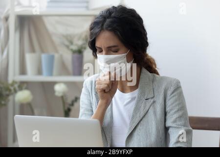 Une femme malsaine dans le masque médical tousse sur le lieu de travail Banque D'Images