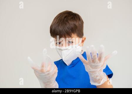 Un garçon caucasien portant un masque et des gants chirurgicaux gestuant avec ses mains se protégeant des maladies respiratoires. Masque facial pour une protection contre l'extérieur Banque D'Images