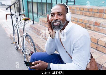 Homme africain américain assis sur les escaliers et à l'aide de son téléphone Banque D'Images