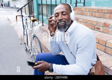 Homme africain américain assis sur les escaliers et à l'aide de son téléphone Banque D'Images