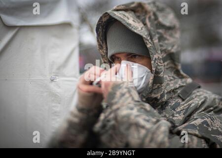 Sergent-maître de la Garde nationale aérienne du New Jersey. Jason Mell, 108ème Groupe médical, met sur un masque de protection N 95 avant d'aider à un site de test communautaire COVID-19 au Centre des arts de la Banque PNC le 23 mars 2020 à Holmdel, dans le New Jersey. Banque D'Images