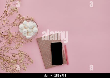 fleurs de gypsophila plat, téléphone mobile et un journal sur fond rose, vue du dessus. espace vide pour le texte. Banque D'Images