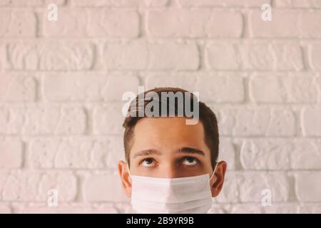 Portrait d'une tête de médecin fatiguée effrayée portant un masque de protection et regardant sur l'espace de copie. Jeune homme épuisé dans le masque médical blanc sur le visage pour Banque D'Images