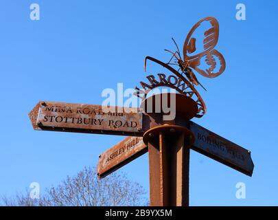 Poteau rouillé de marqueur de fer à Narroways Millenium Green à St Werburghs Bristol UK avec papillon symbolisant le retour de la région à la nature Banque D'Images