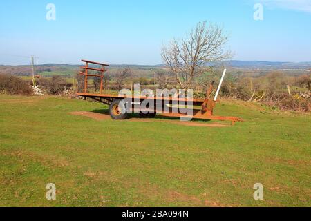 Assise stationnée dans le coin d'un champ, cette remorque extra-robuste attend les balles de foin qu'elle transporte habituellement du champ à la ferme. Banque D'Images