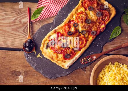 Pizza longue au parmesan sur planche en bois. Pepperoni et poivrons sur pizza au fromage Banque D'Images