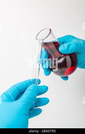 Laboratoire de recherche en médecine. Transfusion d'un liquide chimique à partir d'une fiole dans un tube à essai Banque D'Images