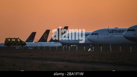 25 mars 2020, Hessen, Francfort-sur-le-Main: Les avions passagers Lufthansa se trouvent sur la piste fermée au nord-ouest de l'aéroport de Francfort, devant le ciel orange-rouge du soir. Lufthansa a stationné des avions qui n'ont pas été nécessaires pendant la crise de Corona. Photo: Arne Dedert/dpa Banque D'Images