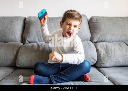 Un garçon excité qui joue à des jeux vidéo à la maison Banque D'Images