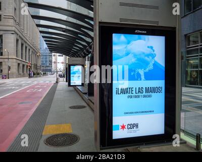 Chicago, Illinois, États-Unis. 24 mars 2020. Une station de bus vide sur la rue Washington et des panneaux électroniques de langue espagnole exhortant les gens à se laver les mains pendant la pandémie COVID-19. Banque D'Images