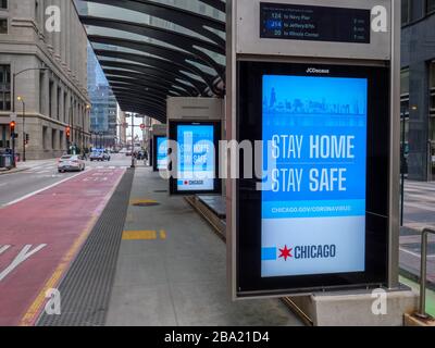 Chicago, Illinois, États-Unis. 24 mars 2020. Une station de bus vide sur la rue Washington et des panneaux electronci exhortant les gens à rester à la maison pendant la pandémie COVID-19. Banque D'Images