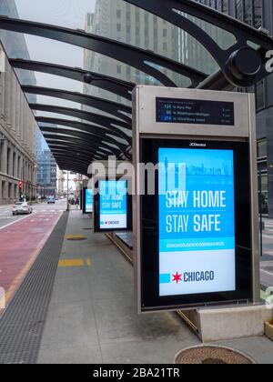 Chicago, Illinois, États-Unis. 24 mars 2020. Une station de bus vide sur la rue Washington et des panneaux electronci exhortant les gens à rester à la maison pendant la pandémie COVID-19. Banque D'Images