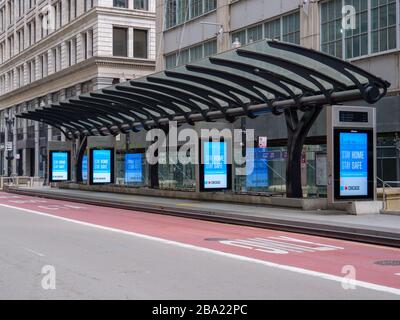 Chicago, Illinois, États-Unis. 24 mars 2020. Une gare routière vide sur Washington Street et des panneaux électroniques exhortant les gens à rester chez eux pendant la pandémie COVID-19. Banque D'Images