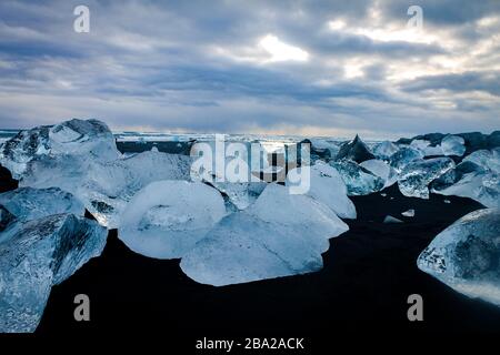 Petites icebergs à la forme différente, ce qui contraste énormément avec la plage de sable noir Banque D'Images