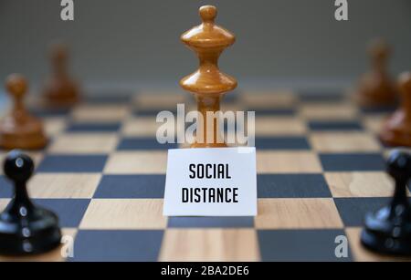 Les pièces d'échecs de concept expriment des distanciation sociale avec le tableau blanc et le texte distance sociale devant la pièce centrale sur le tableau d'échecs. Banque D'Images