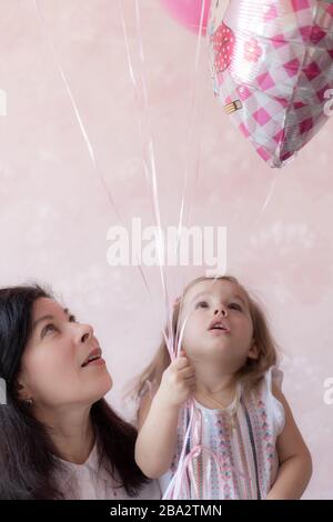 Grand-mère avec petite-fille regarder tenir des ballons dans les mains. Grand-mère avec petite-fille tenir des ballons dans leurs mains et regarder vers le haut. Banque D'Images