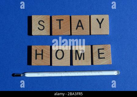 Restez à la maison, les mots et le thermomètre au mercure sur fond bleu Banque D'Images
