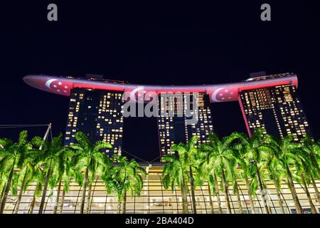 Marina Bay Sands Hôtel la nuit, illuminé avec le drapeau national, Singapour Banque D'Images