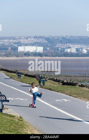 Une jeune fille qui fait de l'exercice quotidien sur la promenade en bord de mer habituellement animée de Mumbles. Un gouvernement est en place pour la pandémie de Covid-19 et les gens ne le sont pas Banque D'Images