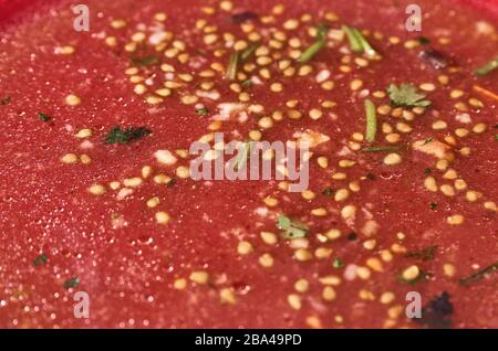 Restes de salade après le repas. Huile, graines de tomate, persil haché sur une seule plaque rouge. Prise de vue macro Banque D'Images