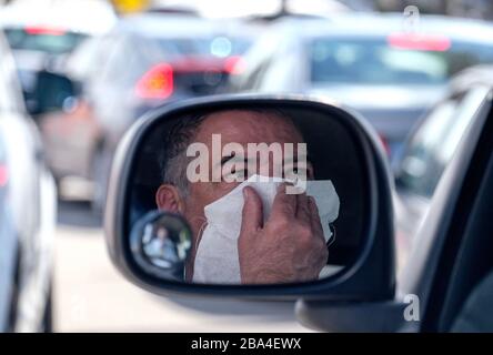 Los Angeles, Californie, États-Unis. 24 mars 2020. Steve Oliveira, 58 ans, portant un masque facial se reflète dans le rétroviseur de son véhicule alors qu'il attend dans son véhicule doublé à l'extérieur du Centre chrétien de Crenshaw pour COVID-19 dans le sud de Los Angeles, le mercredi 25 mars 2020. Gov de Californie. Gavin Newsom a publié jeudi un ordre de séjour à domicile à l'échelle de l'État pour que les résidents s'aventurant à l'extérieur seulement pour des emplois essentiels, des errands et un certain exercice, en raison des préoccupations de coronavirus. Crédit: Ringo Chiu/ZUMA Wire/Alay Live News Banque D'Images