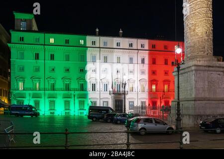 Rome, Italie - 24 mars 2020: Palazzo Chigi, siège du gouvernement italien, façade du bâtiment illuminé avec les couleurs du drapeau italien. Coronavirus urgence Italie. Banque D'Images