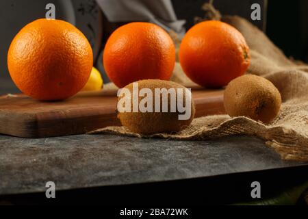 Oranges et kiwies dans une rangée sur un tableau de découpe. Banque D'Images