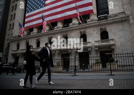 Pékin, États-Unis. 18 mars 2020. Les piétons portant des masques de visage marchent devant la Bourse de New York (NYSE) à New York, aux États-Unis, le 18 mars 2020. Crédit: Michael Nagle/Xinhua/Alay Live News Banque D'Images
