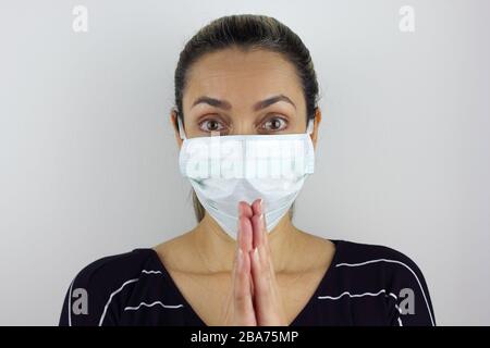 Femme d'Amérique latine portant un masque de virus et priant pour la prévention du virus corona Banque D'Images