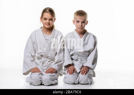 Deux étudiants judo s'assoient sur leurs genoux et regardent dans le cadre Banque D'Images