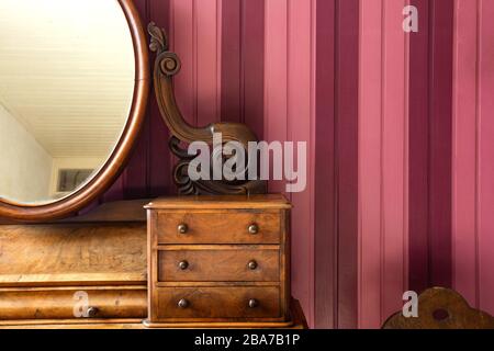 Table de maquillage ancienne vintage avec miroir rond contre mur en bois rose, design rétro Banque D'Images