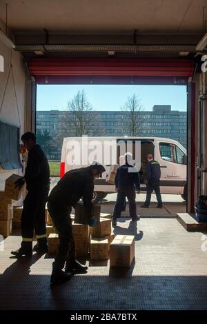 25 mars 2020, Saxe-Anhalt, Arneburg: Soldats du Bataillon logistique 171 et pompiers du Centre technique de lutte contre les incendies du comté de Stendal transportent des boîtes d'équipement de protection dans un garage. L'équipement de protection comprend des masques respiratoires FFP, des masques chirurgicaux, des vêtements de protection, des lunettes de protection, des kits d'échantillonnage et des gants en caoutchouc commandés par le gouvernement fédéral pour les États fédéraux et distribués par les soldats du Bataillon logistique 171 aux districts de Saxe-Anhalt. Le district de Stendal distribuera le matériel de protection dans la matinée du 26.03.2020 à la retraite h Banque D'Images