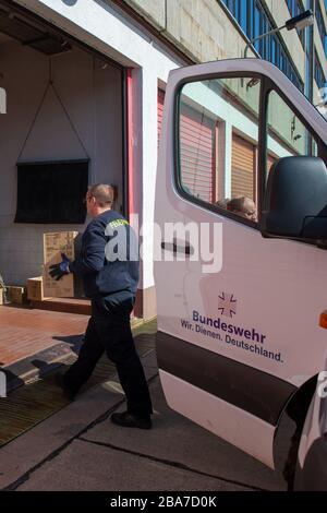 25 mars 2020, Saxe-Anhalt, Arneburg: Un pompier du centre technique de pompiers du district de Stendal transporte une boîte d'équipement de protection dans un garage. L'équipement de protection comprend des masques respiratoires FFP, des masques chirurgicaux, des vêtements de protection, des lunettes de protection, des kits d'échantillonnage et des gants en caoutchouc commandés par le gouvernement fédéral pour les États fédéraux et distribués par les soldats du Bataillon logistique 171 aux districts de Saxe-Anhalt. Le district de Stendal distribuera le matériel de protection dans la matinée du 26.03.2020 aux maisons de retraite, aux hôpitaux et à l'outpatien Banque D'Images