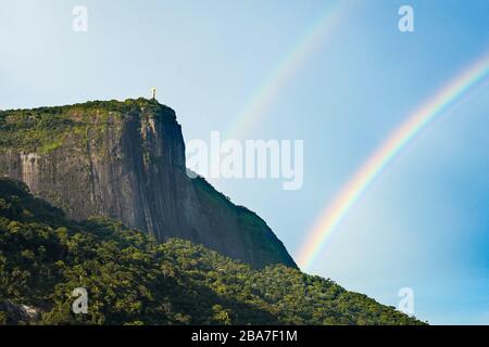 Statue de Jésus-Christ au sommet d'une falaise avec L'arc-en-ciel dans le ciel bleu de Rio de Janeiro Banque D'Images